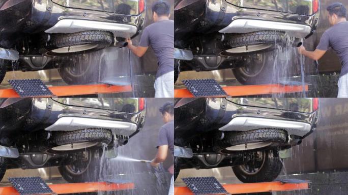洗车和细节。专业工人正在洗车时用高压清洗机洗车。车库汽车服务的工人正在用水管洗车