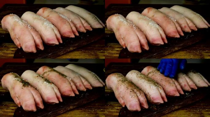 戴着橡胶手套的人的手在木制厨房板上撒上盐和胡椒粉生猪腿。