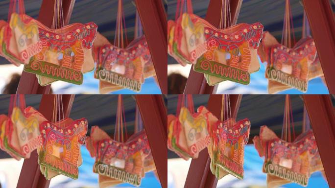 悬挂在节日帐篷下面的马形姜饼。街头拍卖会上袋装糖果。