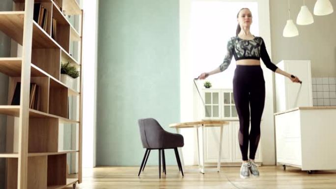 年轻的运动女子正在跳绳在厨房里进行有氧运动训练