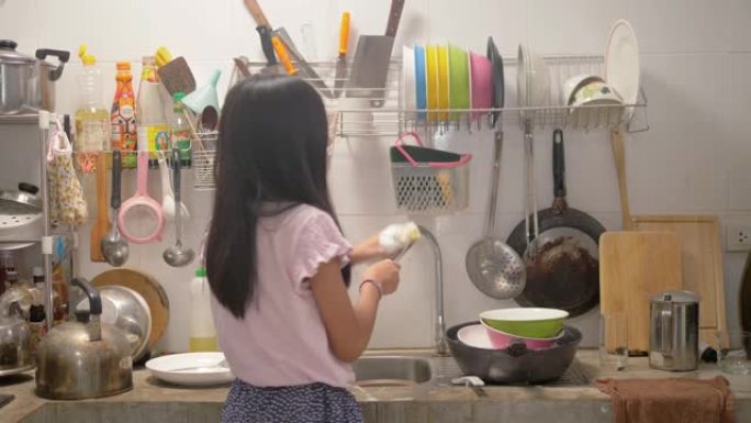 快乐的亚洲女孩在厨房洗碗，在家跳舞。