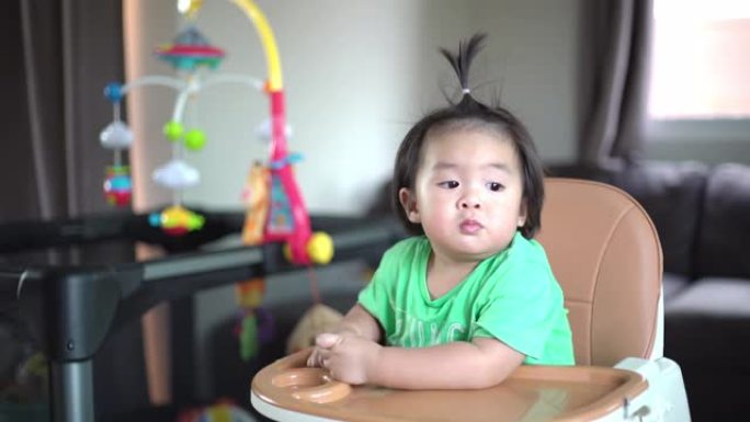 亚洲宝宝在高脚椅上嚼食