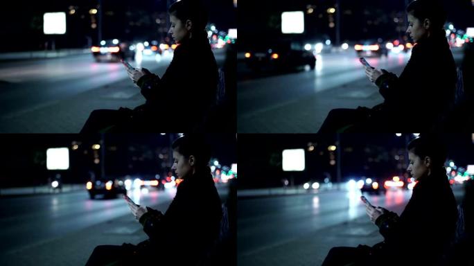 孤独的女人晚上在街上使用手机，夜间交通经过