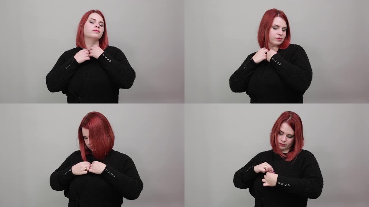 穿着黑色毛衣的红发胖女人时尚女人在扣眼里扣一个纽扣