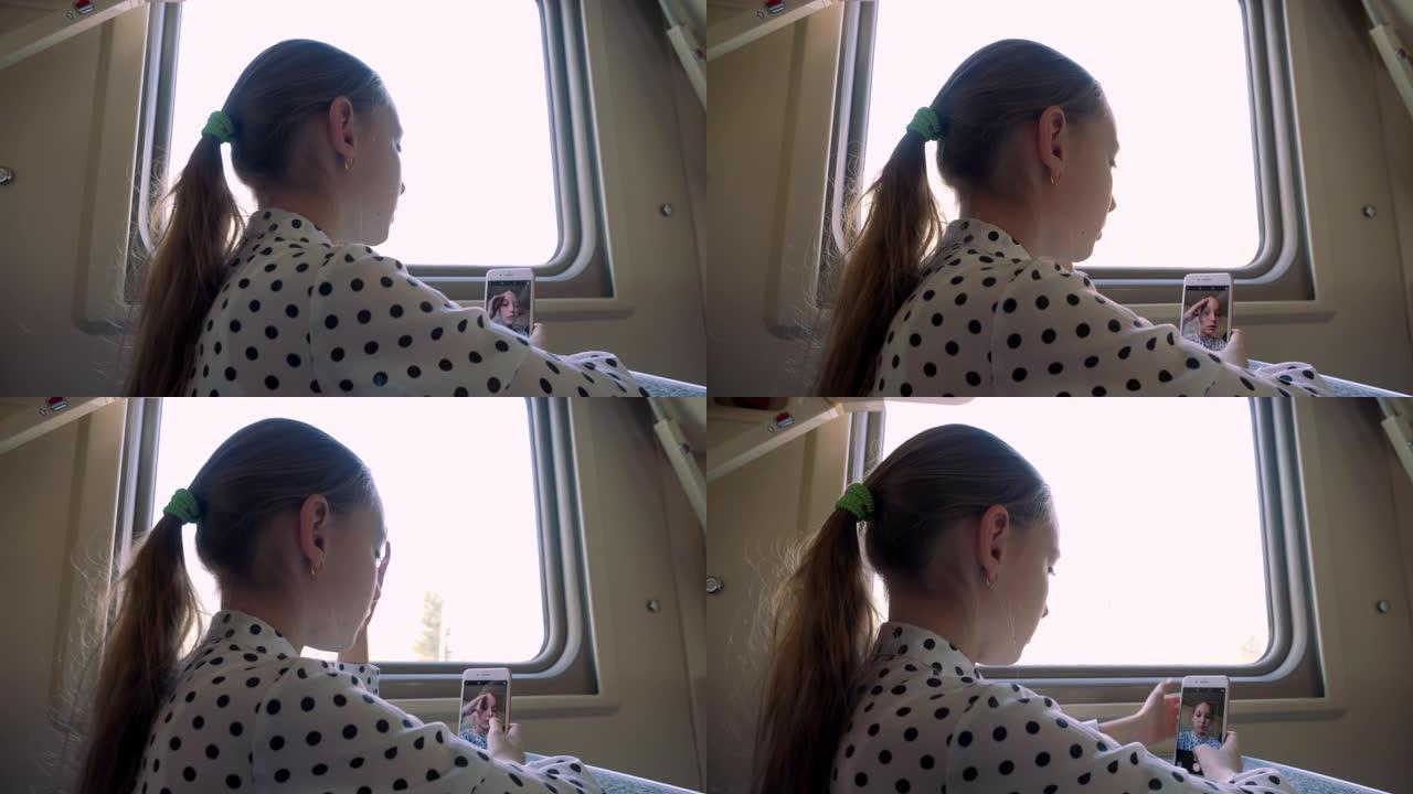 旅游女孩少年在窗口背景上拍摄关于火车旅行的视频博客。旅行少女在火车旅行中为社交网络中的在线故事摆姿势