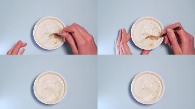 一个人吃一勺无麸质素食酸奶和新鲜水果。女性的手在白色背景上sc了一勺酸奶，孤立的4k
