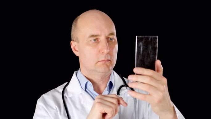 男性医生在黑色背景上触摸未来智能手机上的透明屏幕。穿着白大褂的医务人员使用高科技手机。