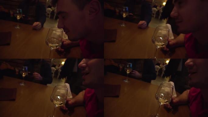 一名男子从餐厅的玻璃杯中嗅出酒味，并享受着香气