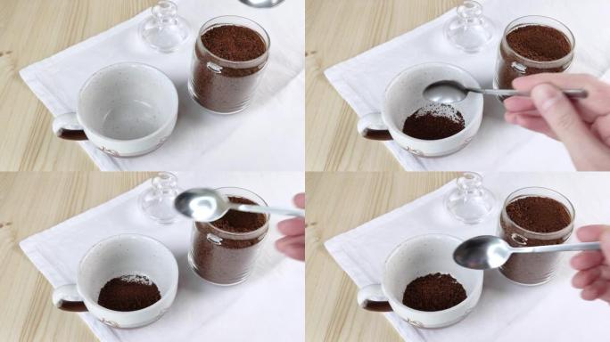 用勺子将玻璃罐中的冻干咖啡放入杯子中