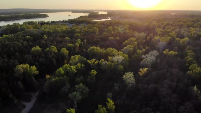 日落时，无人机在森林和沿河的道路上进行空中勘测。