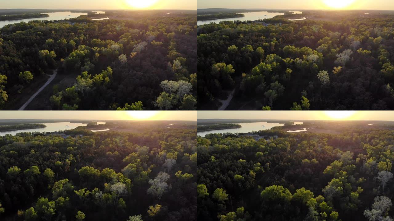 日落时，无人机在森林和沿河的道路上进行空中勘测。
