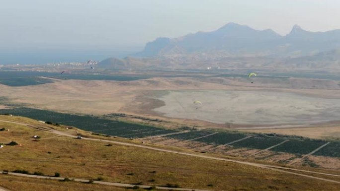从山脉脚下的空气谷看远处干涸的湖海和翱翔的滑翔伞