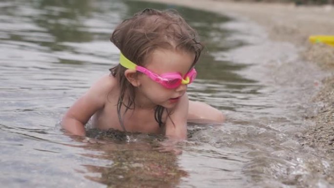 可爱的小女孩，戴着潜水镜试图游泳