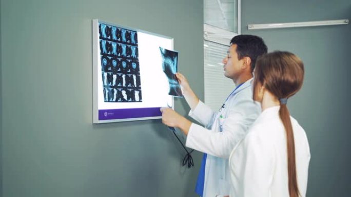 男医生正在白板上悬挂x射线照片。