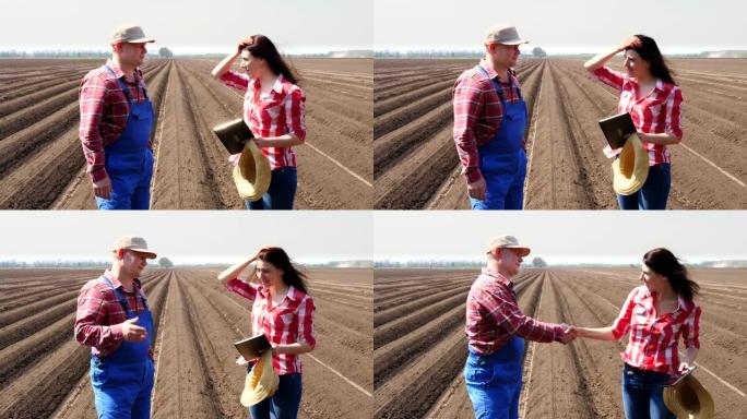 农民和农艺师站在田间的土壤行之间，用数字平板电脑谈论马铃薯栽培的质量。握手。现代农业。春天阳光明媚的