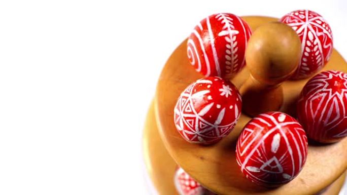 带有乌克兰民间图案的红色复活节彩蛋躺在木制架子上旋转，放在白色背景上的彩蛋上。乌克兰传统鸡蛋pisa