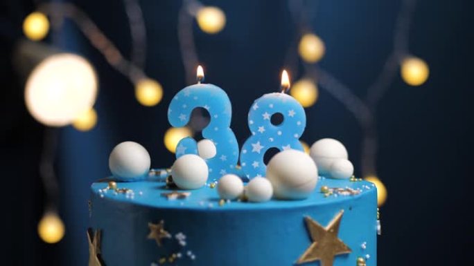 生日蛋糕编号38星星天空和月亮概念，蓝色蜡烛被打火机点燃，然后吹灭。如果需要，请在屏幕右侧复制空间。