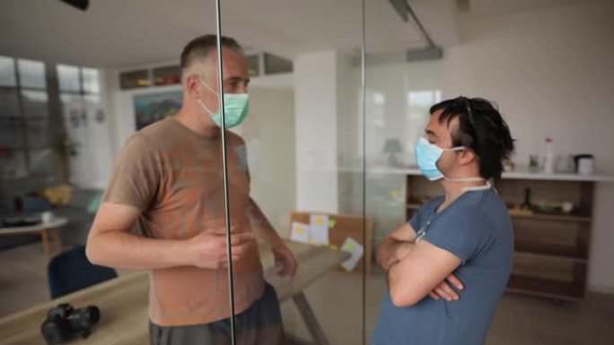 在新型冠状病毒肺炎大流行期间，朋友与玻璃推拉门交谈