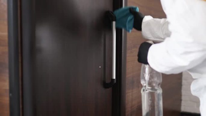 使用抗菌喷雾器将手放在医用手套上，擦拭用于消毒门把手。消毒和清洁门把手。细菌，细菌，新型冠状病毒肺炎