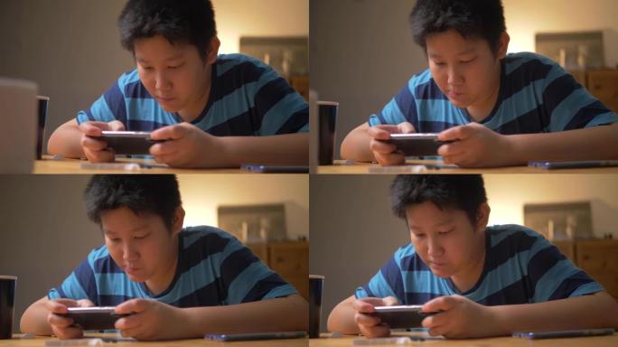 亚洲青春期男孩在晚上在家玩网络游戏。