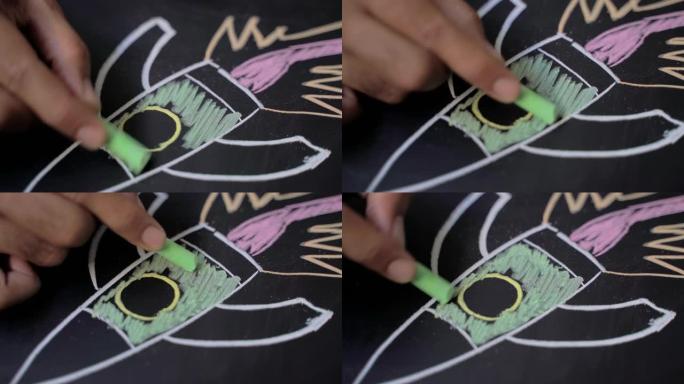 教育理念。特写男性的手是用绿色粉笔在黑板上画火箭。