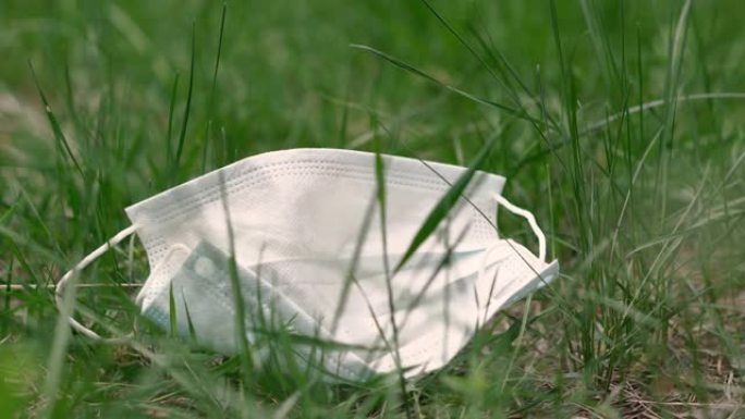 医用口罩。废弃的医用口罩躺在绿色的草坪上。