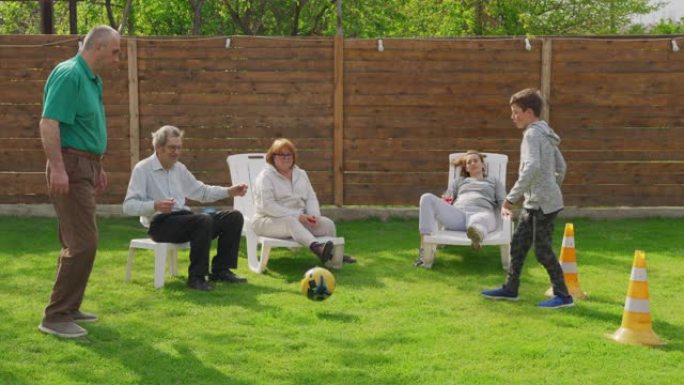 多代家庭一起在花园里踢足球。
