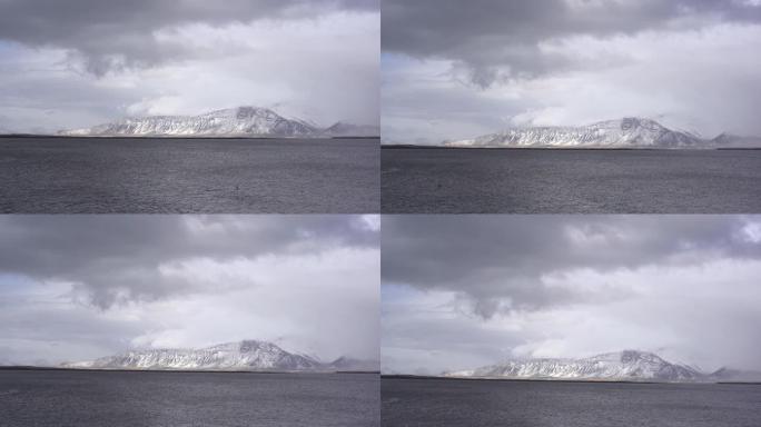 冰岛大西洋沿岸的一座冰雪覆盖的山脉。从另一边看，或者从大海看。多云的天气，浓云密布。