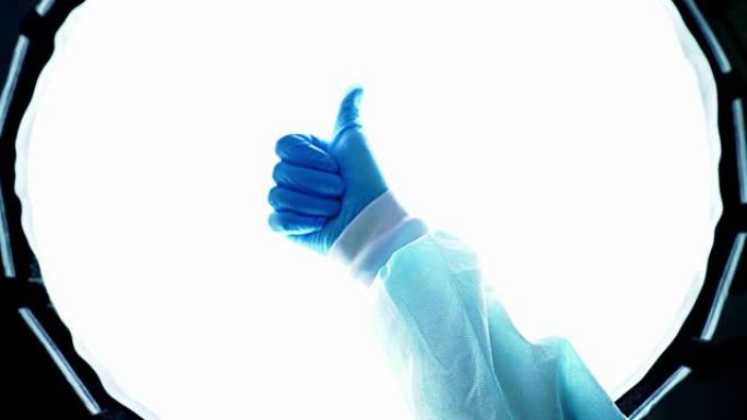 戴着蓝色医疗手套的医生显示拇指向上。战胜疾病。
