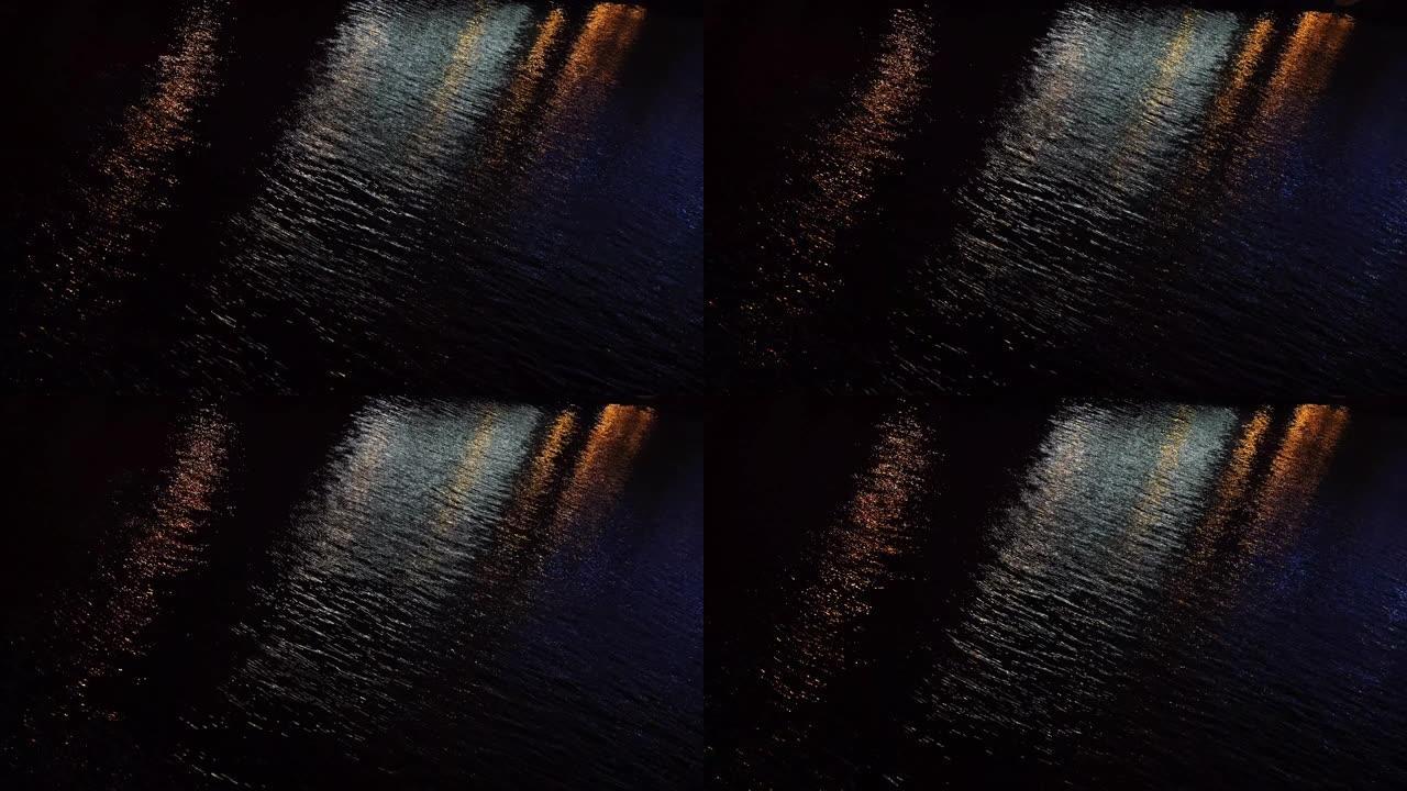 夜间池塘黑暗水面的特写镜头，城市灯光的反射。概念。美丽的夜景