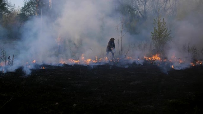 妇女试图通过从塑料瓶中倒水来阻止森林即将发生的大火。