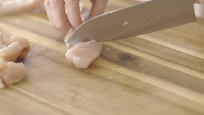 在木制砧板上手工切割鸡胸肉