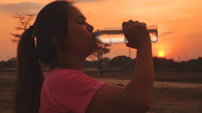 女人在日落时喝水短暂的休息休息放松补充能