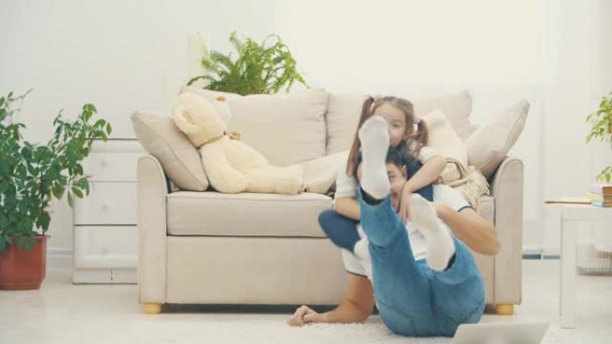 父亲将他漂亮的小女儿抱在肩膀上，然后他们在4k视频中摔倒在地板上。