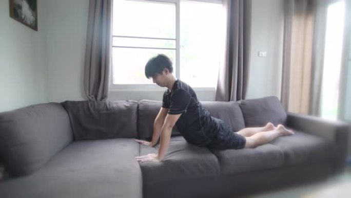 亚洲男人在家沙发上做瑜伽练习