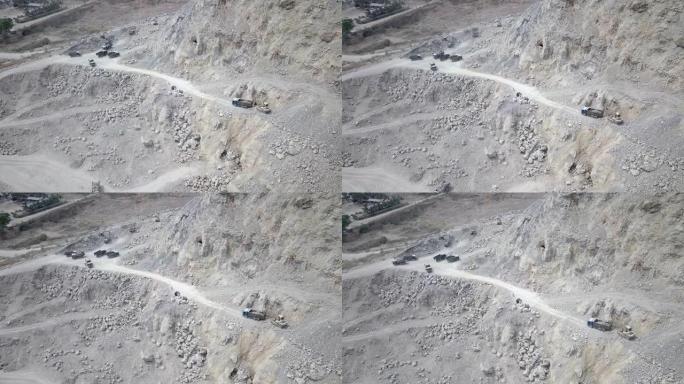 在采石场山上，挖掘机将岩石装载到自卸车中的空中无人机拍摄