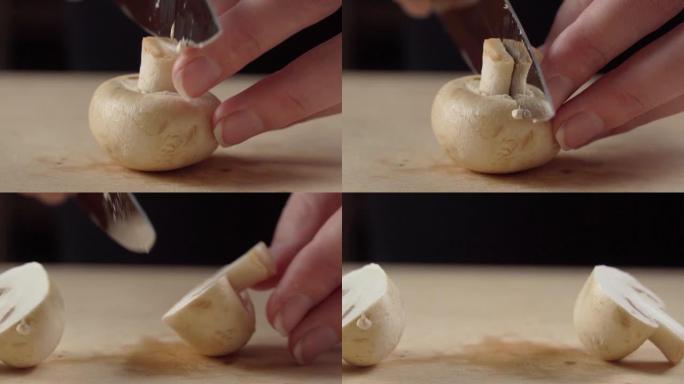 用手指上漂亮修指甲的女性手用菜刀在木制砧板上切蘑菇，特写镜头。钱皮农。女人在家做饭