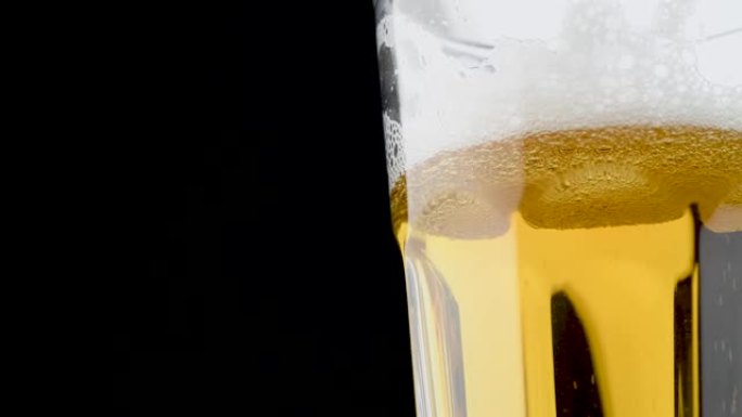 冷光精酿啤酒倒入玻璃杯中。黑色背景上的特写视频。