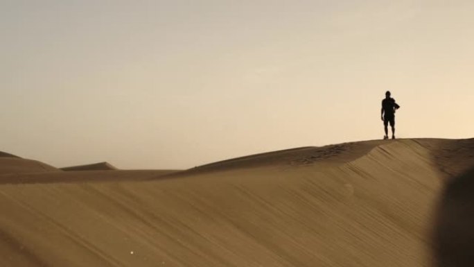 沿着沙漠中的沙丘行走的人