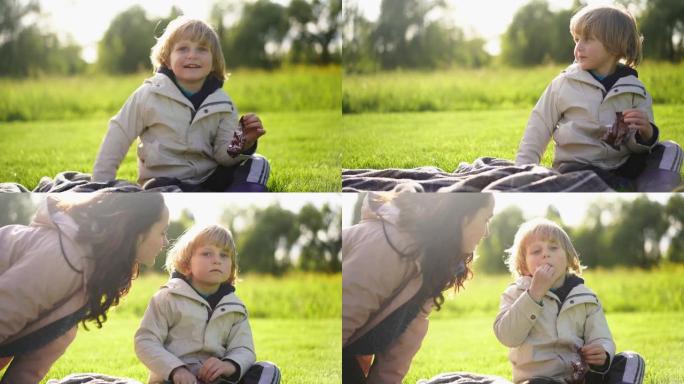 男孩与坐在草地上的女人分享糖果