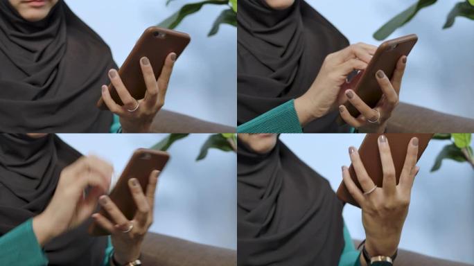一名年轻穆斯林妇女使用喷雾酒精清洁智能手机的手照-冠状病毒covid 19保护意识概念多样性
