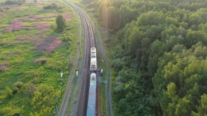 火车在野外的俄罗斯森林中驶入远方。日落时的鸟瞰图。