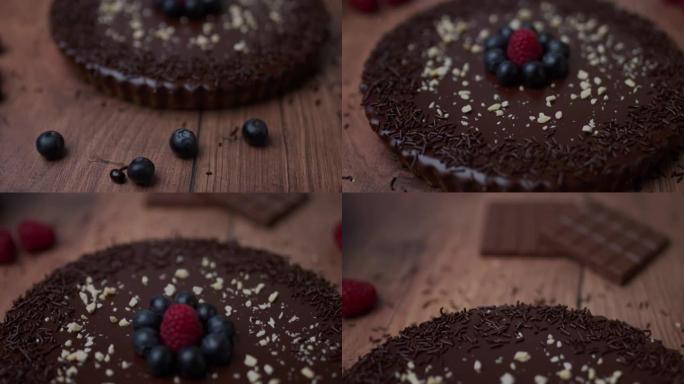 在木桌上摆着精美的现成巧克力蛋糕的特写镜头，上面装饰着水果和时令浆果，成分包括: 蓝莓，覆盆子，巧克