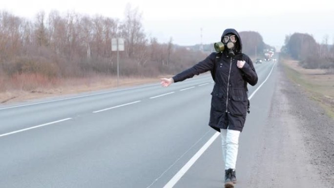 一个戴着防毒面具的女孩站在路边，试图停车。
