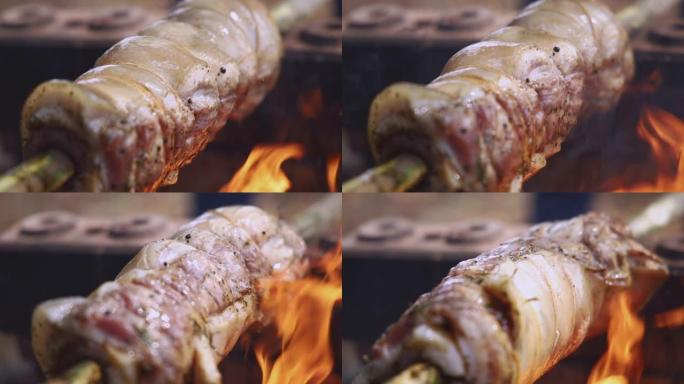 燃烧的柴火在篝火的火焰上滚动烤五花肉