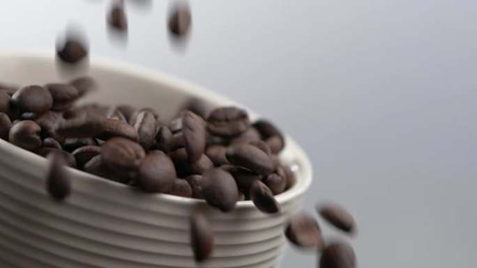 慢动作落下的咖啡豆。装满咖啡豆的咖啡杯