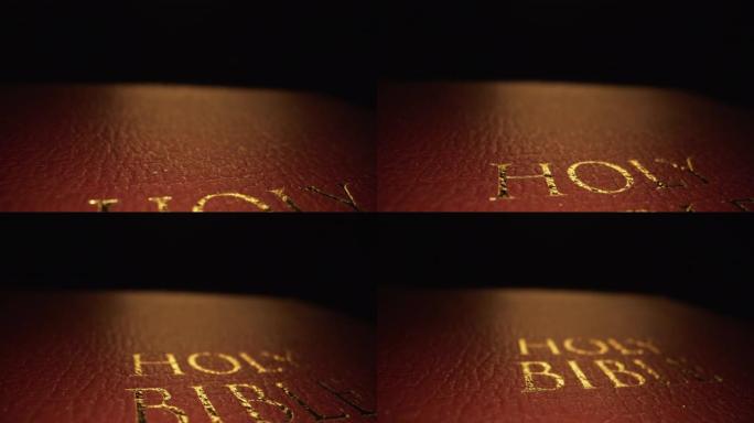 极端微距特写移动滑块揭示拍摄的黄金文字标题“圣经”封面纹理图案书上帝的话在一个黑暗的背景与独特的照明