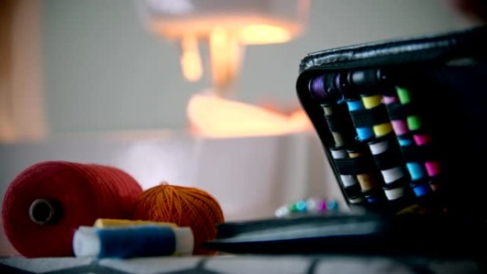 年轻女性设计师使用缝纫机缝制-前景上的缝制配件