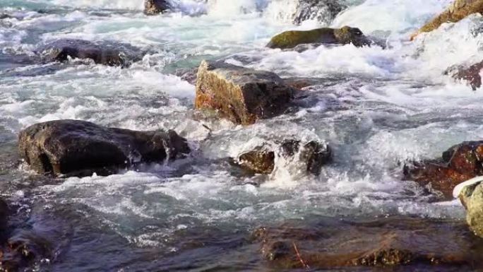 野河流过岩石，形成白色泡沫和波浪。慢动作视频