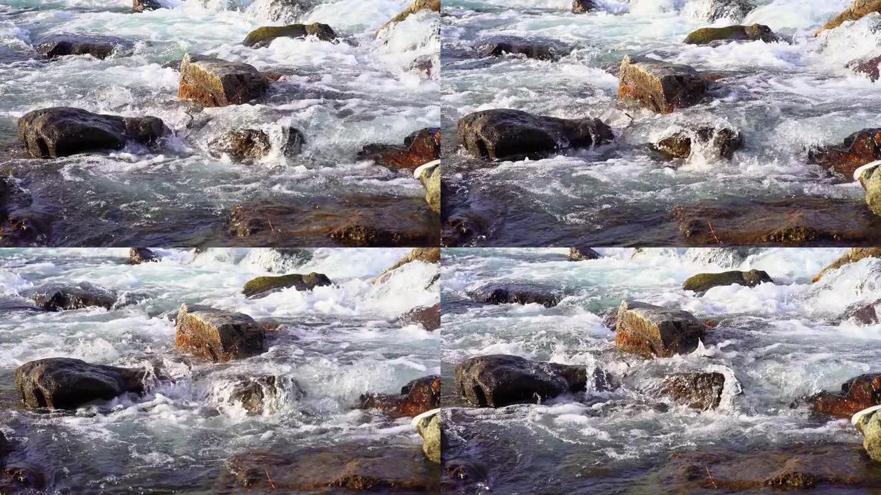 野河流过岩石，形成白色泡沫和波浪。慢动作视频